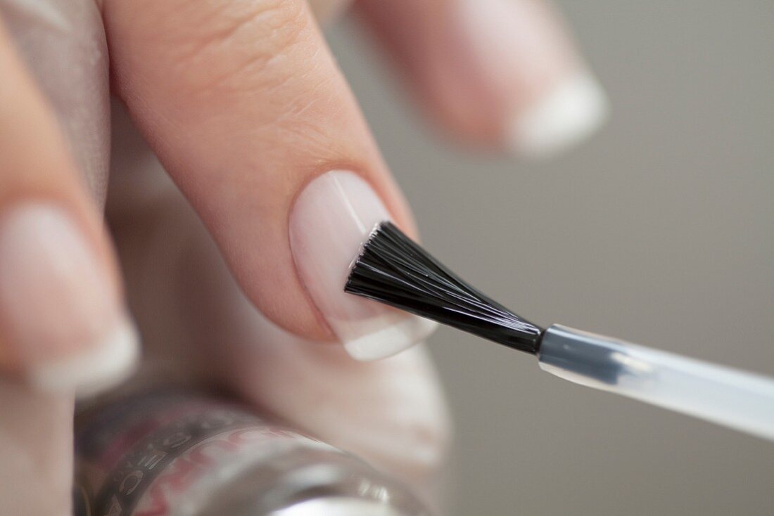 Fingernails being painted with clear nail polish