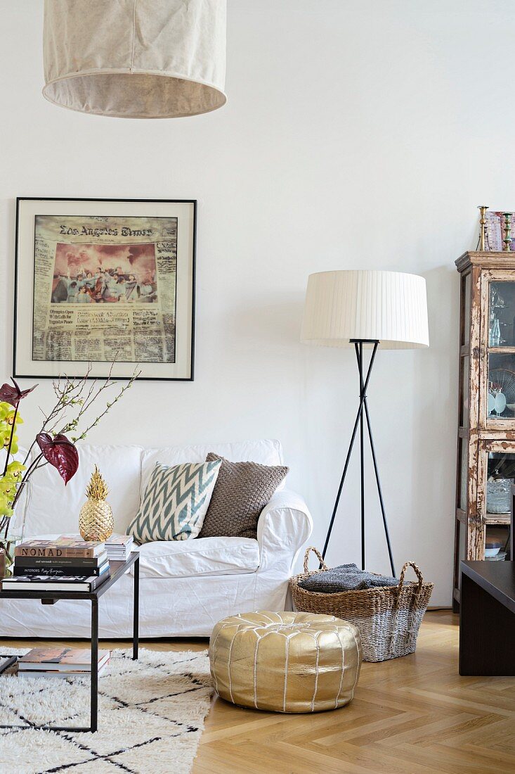 Oak parquet floor, gold pouffe and white loose-covered sofa in comfortable living area