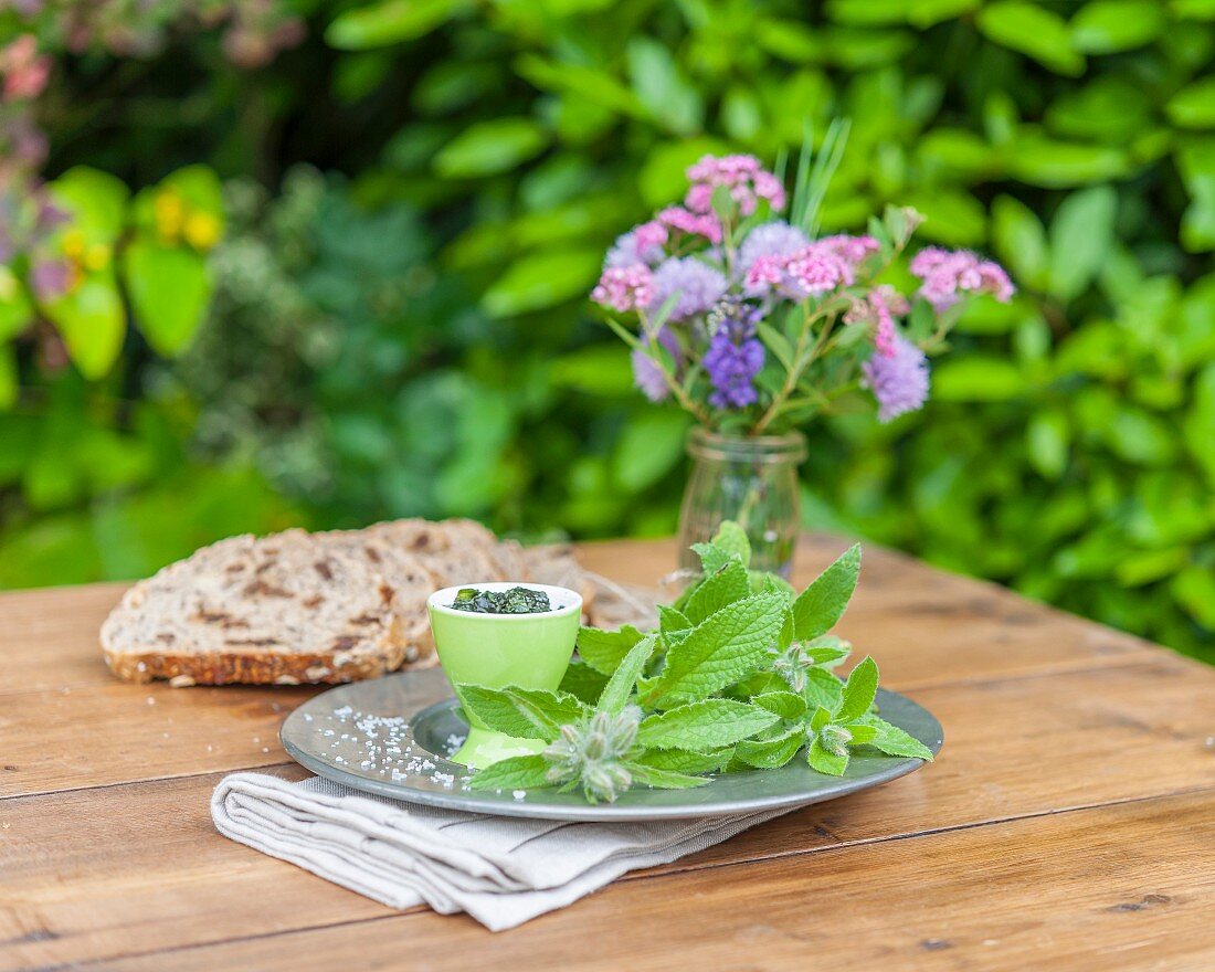 Borretsch, Brotscheiben und Blumenstrauss auf Gartentisch