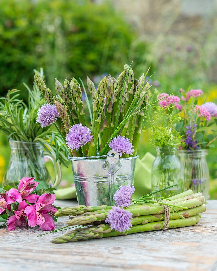 Grüner Spargel und frische Kräuter auf Gartentisch