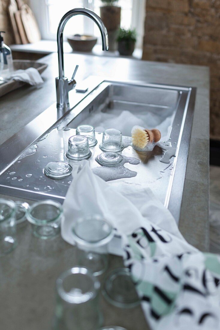 A kitchen island with a stainless steel sink and a drainer in a concrete work surface