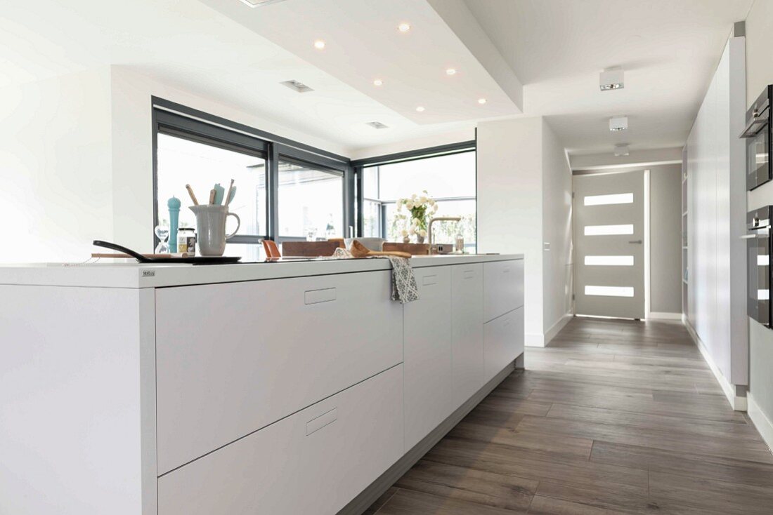 An island with white cupboards in an open-plan designer kitchen