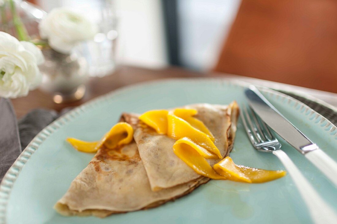 Flambéed lemon and mango crepe on a plate