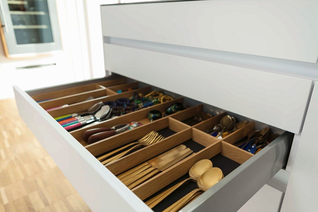 An open cutlery drawer in a kitchen cupboard