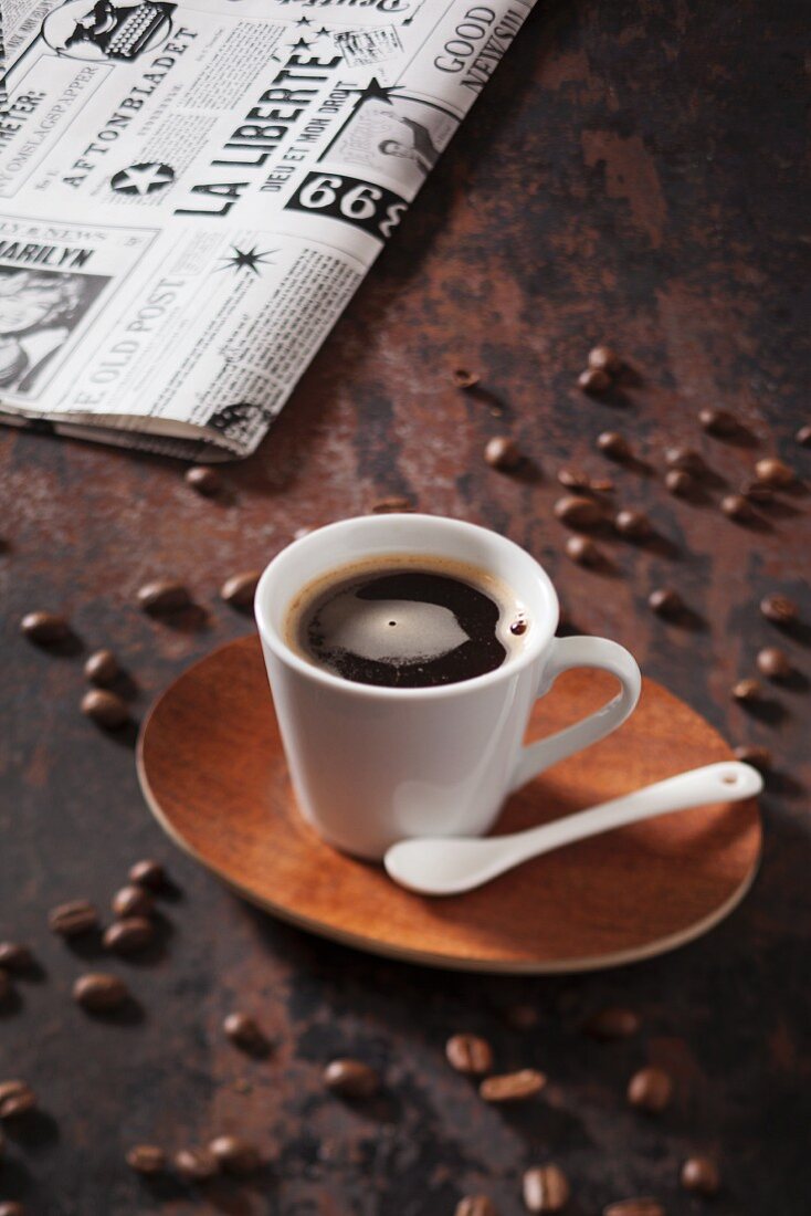 Eine Tasse Kaffee, im Hintergrund Tageszeitung