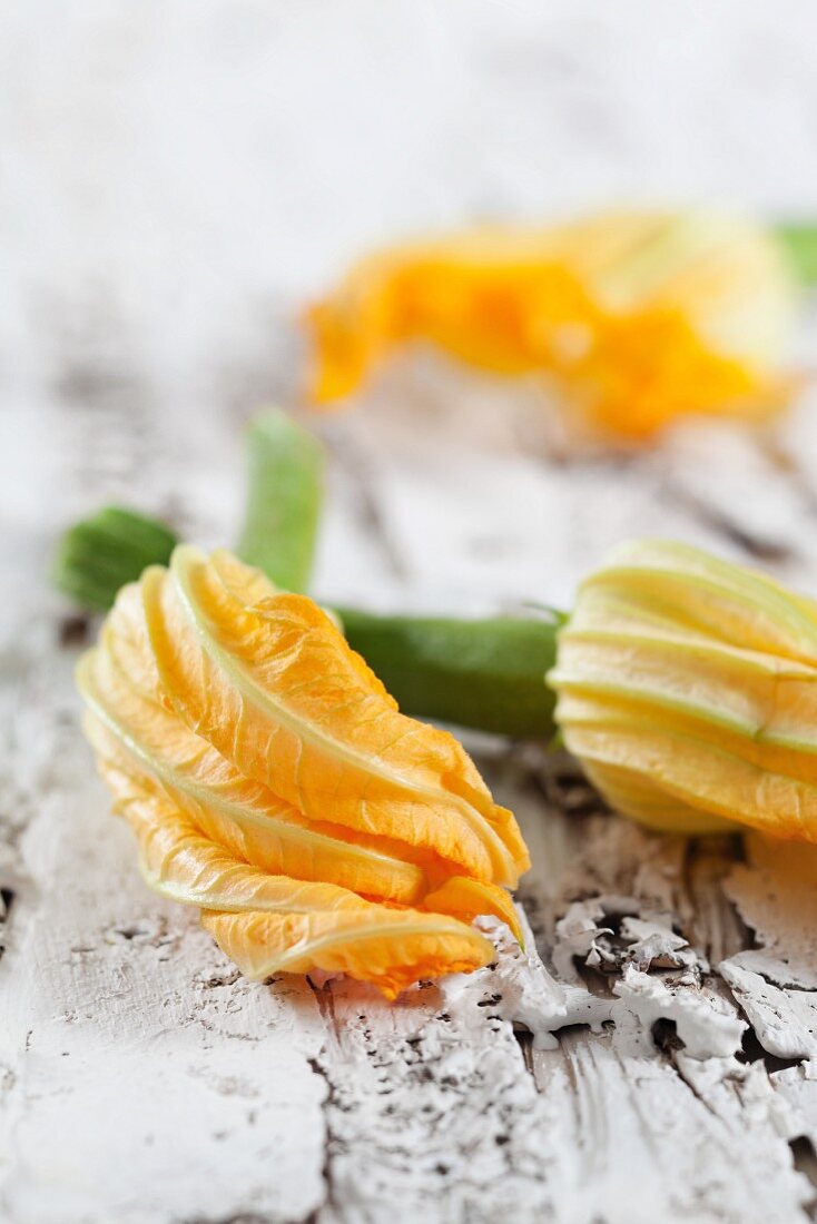 Courgette flowers on a white wooden surface