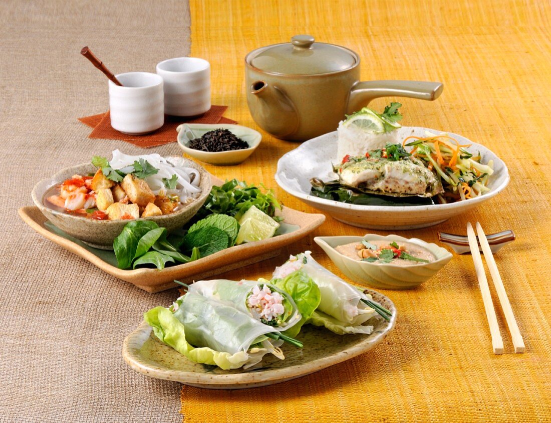 Various Thai dishes on a yellow table runner