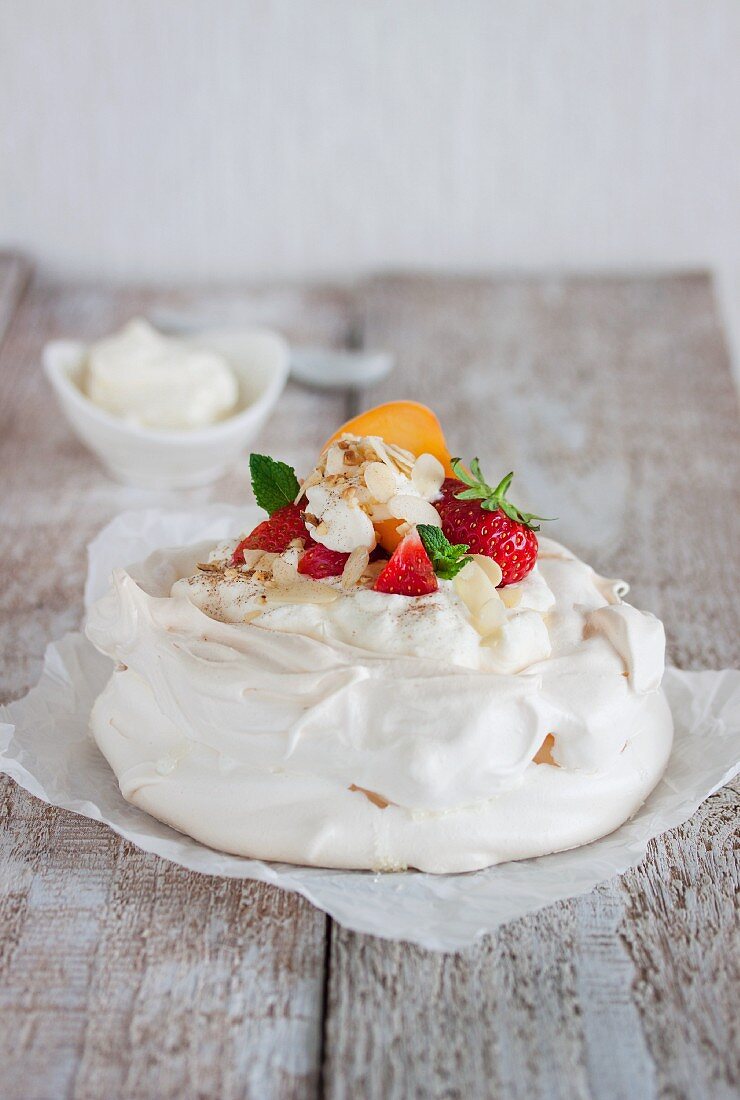 Pavlova with whipped cream, fruit and almonds