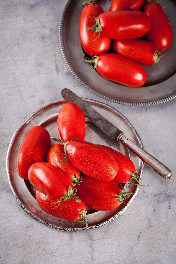 San Marzano Tomaten auf Metallteller mit Messer (Draufsicht)