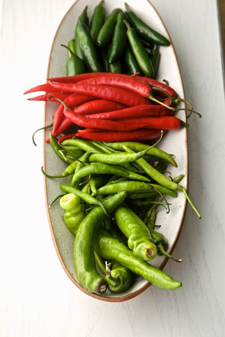 Four different fresh chilli peppers on a plate