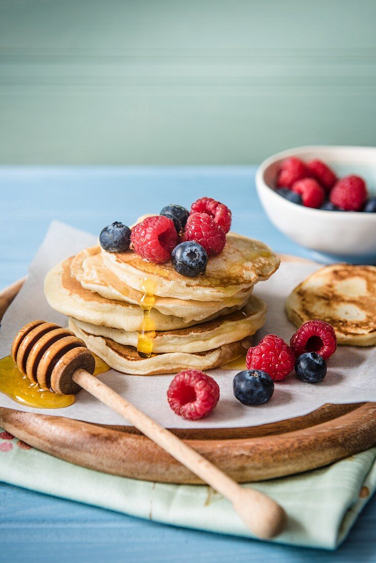 A stack of pancakes with berries and honey
