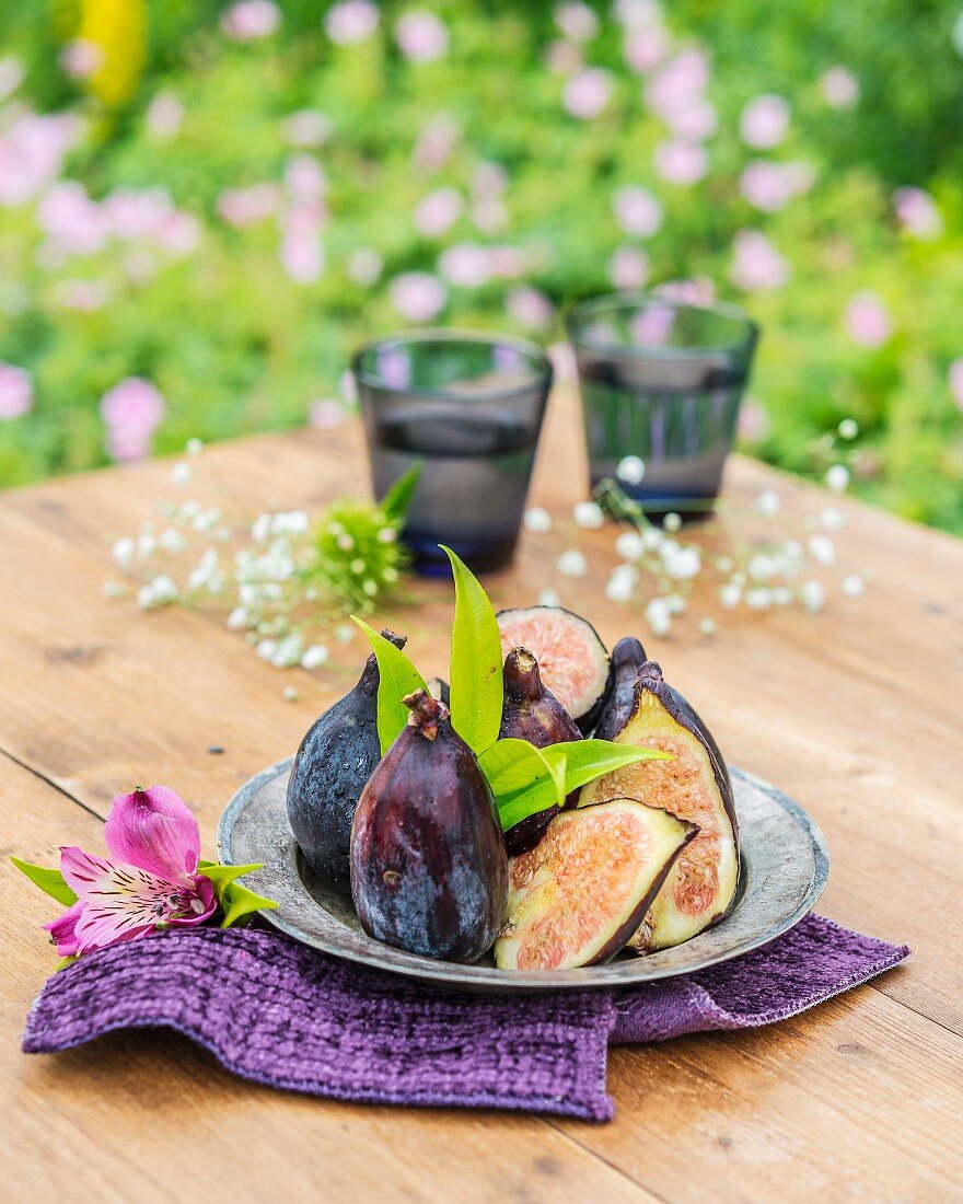 Purple figs on a pewter plate on a garden table
