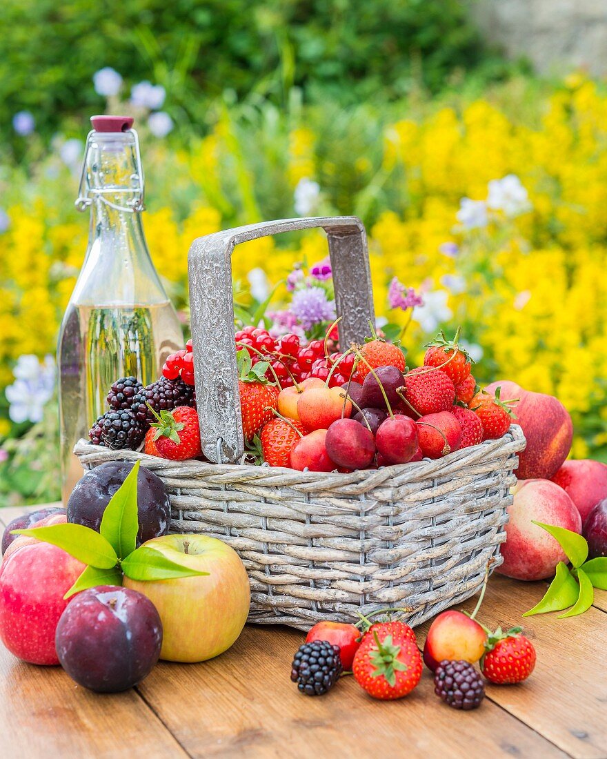 Beeren und Früchte in Korb und daneben auf Gartentisch