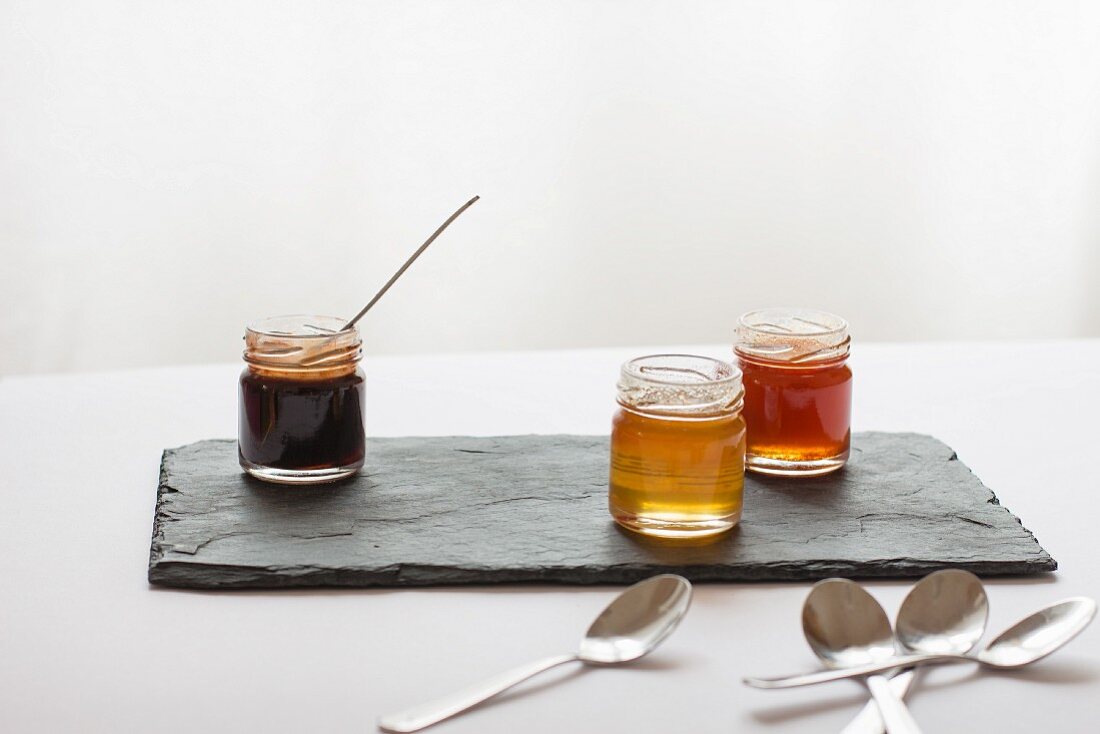 Various jars of honey on a slate platter