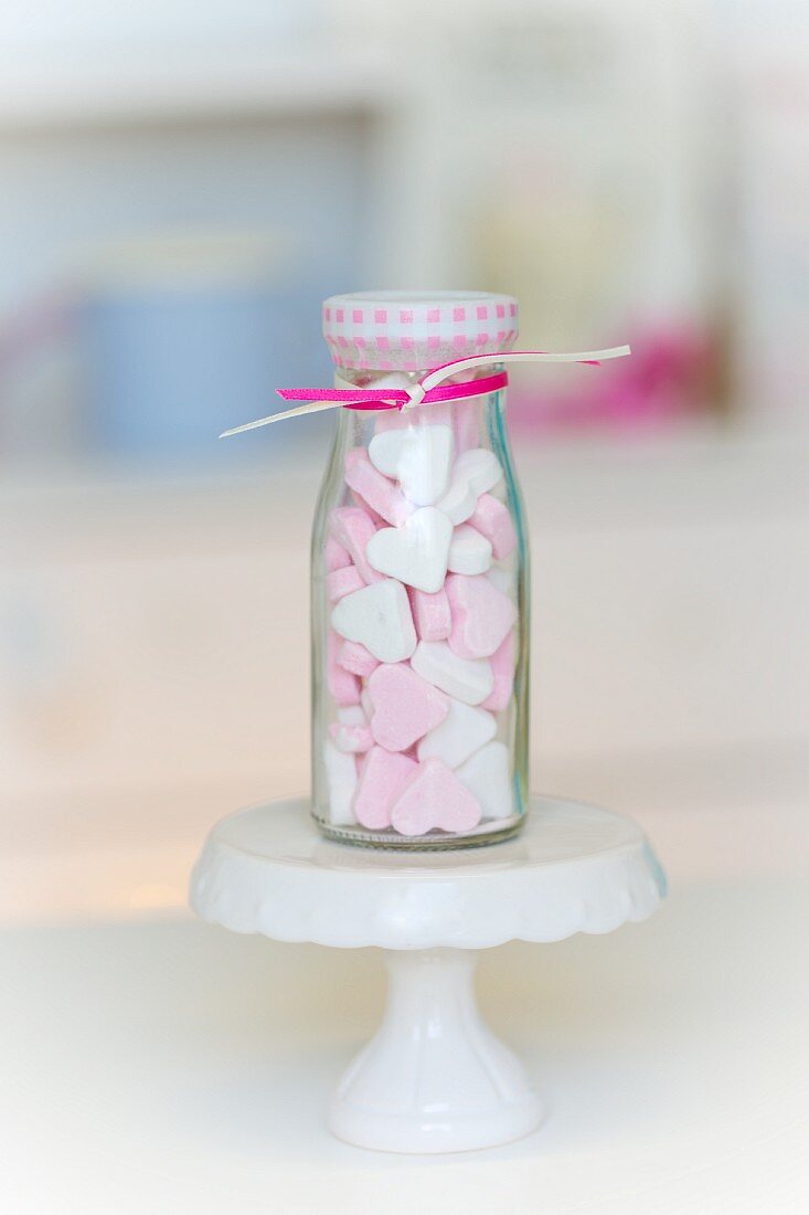 weiße und rosafarbene Pfefferminzherzen in einem kleinen Glasfläschchen