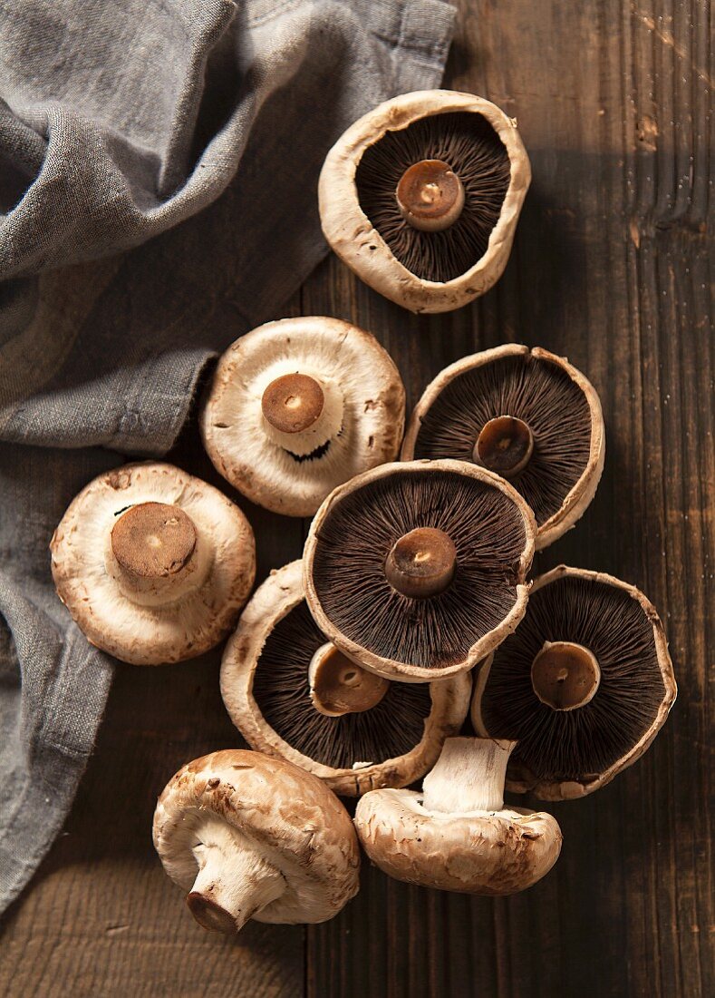 Nine mushrooms on a dark chopping board with a grey linen napkin