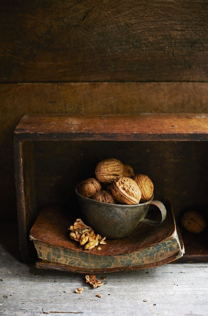 Walnuts in a tin cup on an old book