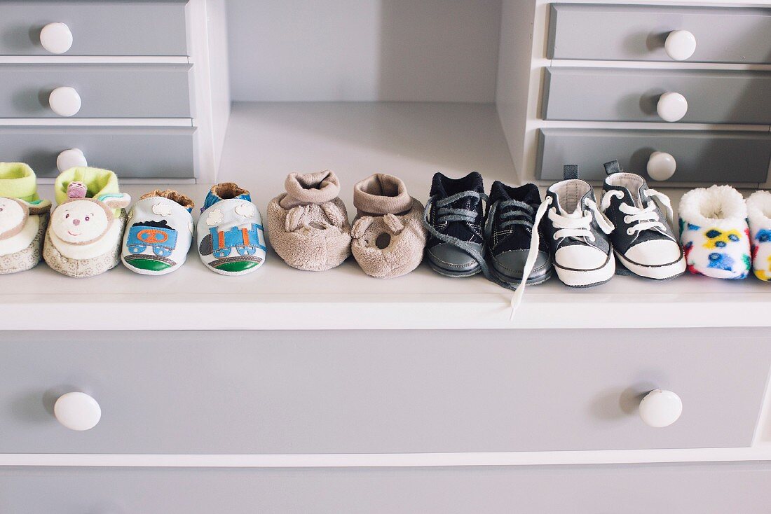 Row of babies booties on grey chest of drawers