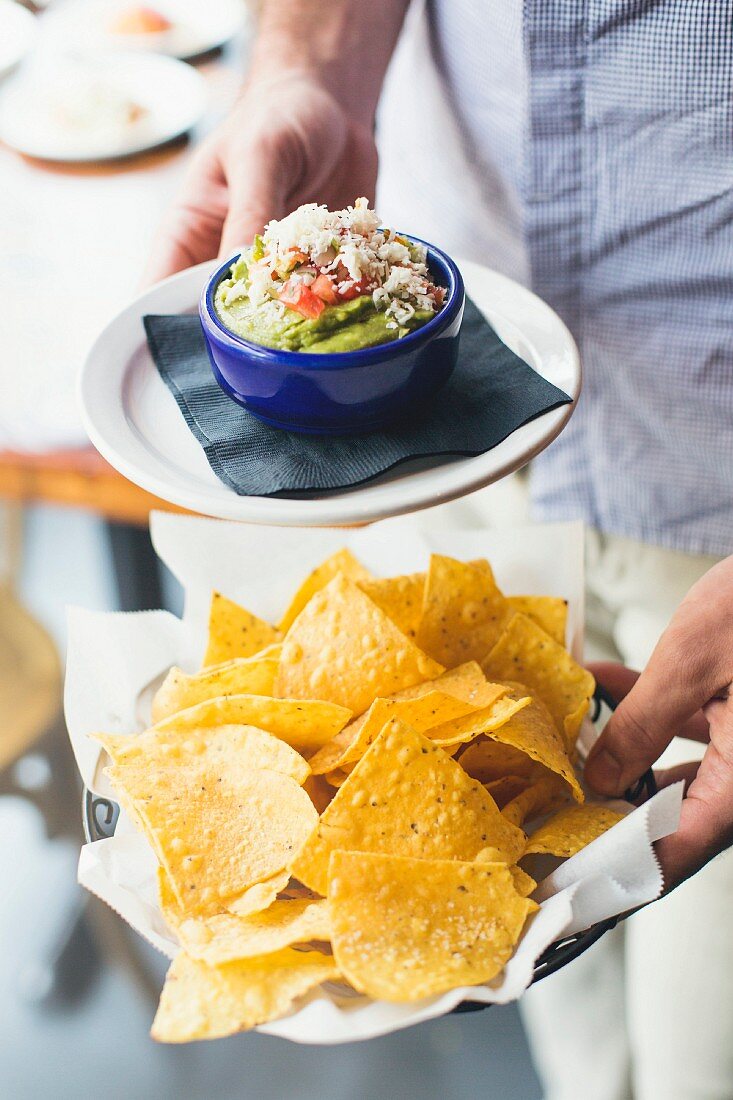 Mann serviert Taco-Chips und Guacamole