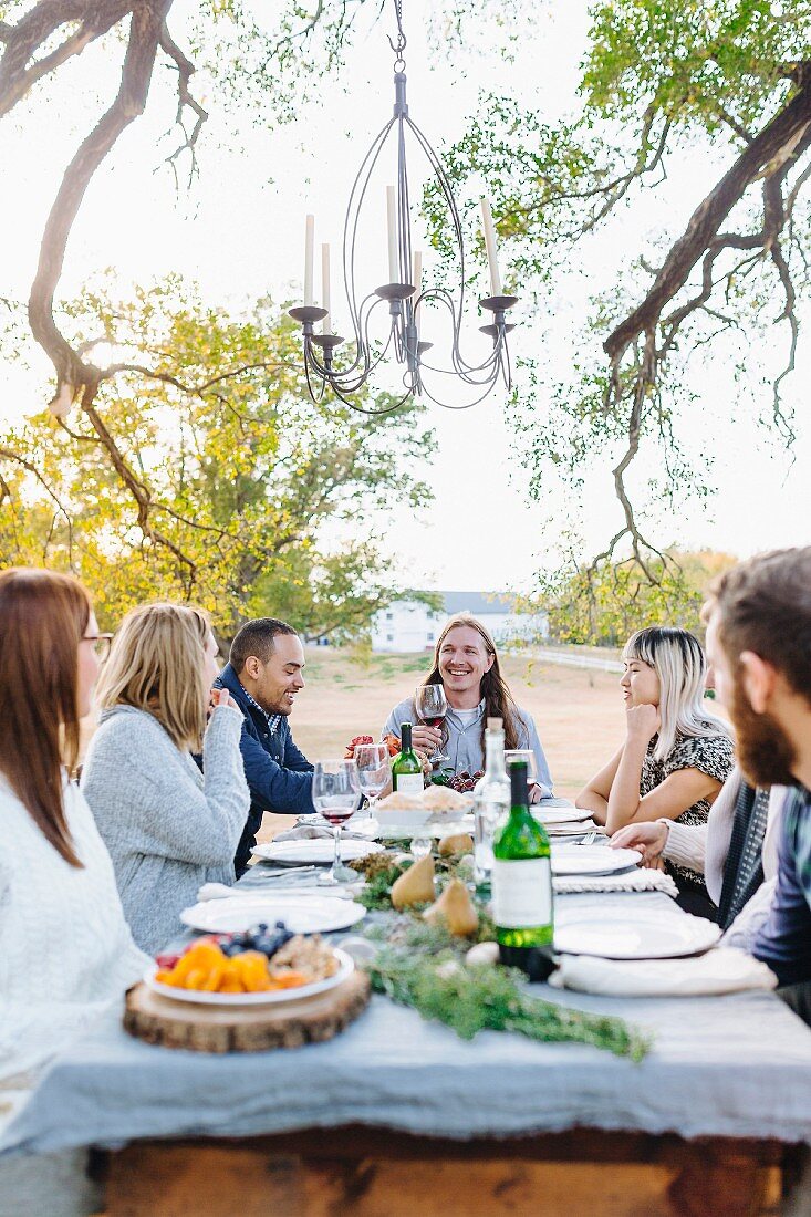 Friends eating together outside at an autumnal decorated table