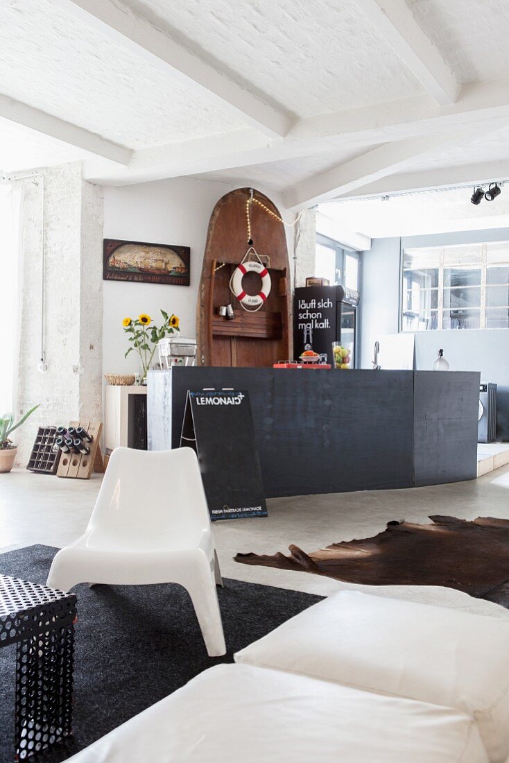 Lifebelt hung from wooden boat stood on end behind black kitchen counter in open-plan living area