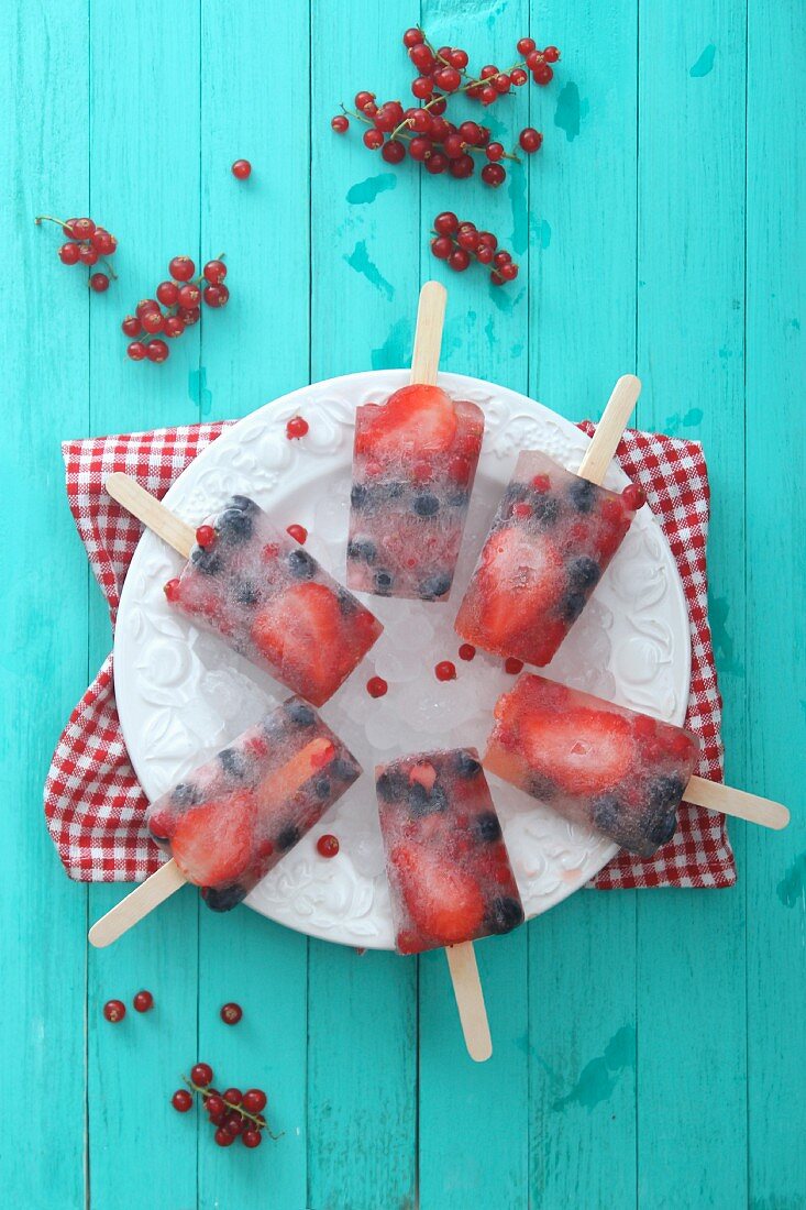 Homemade summer berry ice lollies on a plate (seen from above)