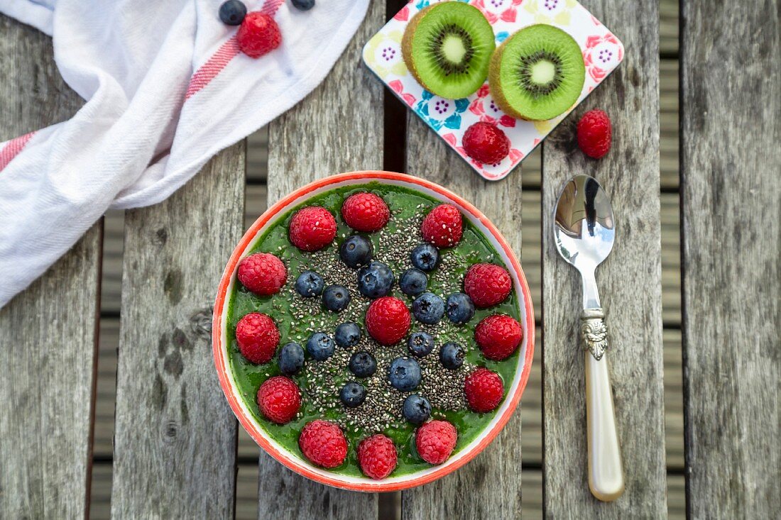 Grüne Smoothie-Bowl mit Kiwi, Himbeeren, Blaubeeren und Chiasamen