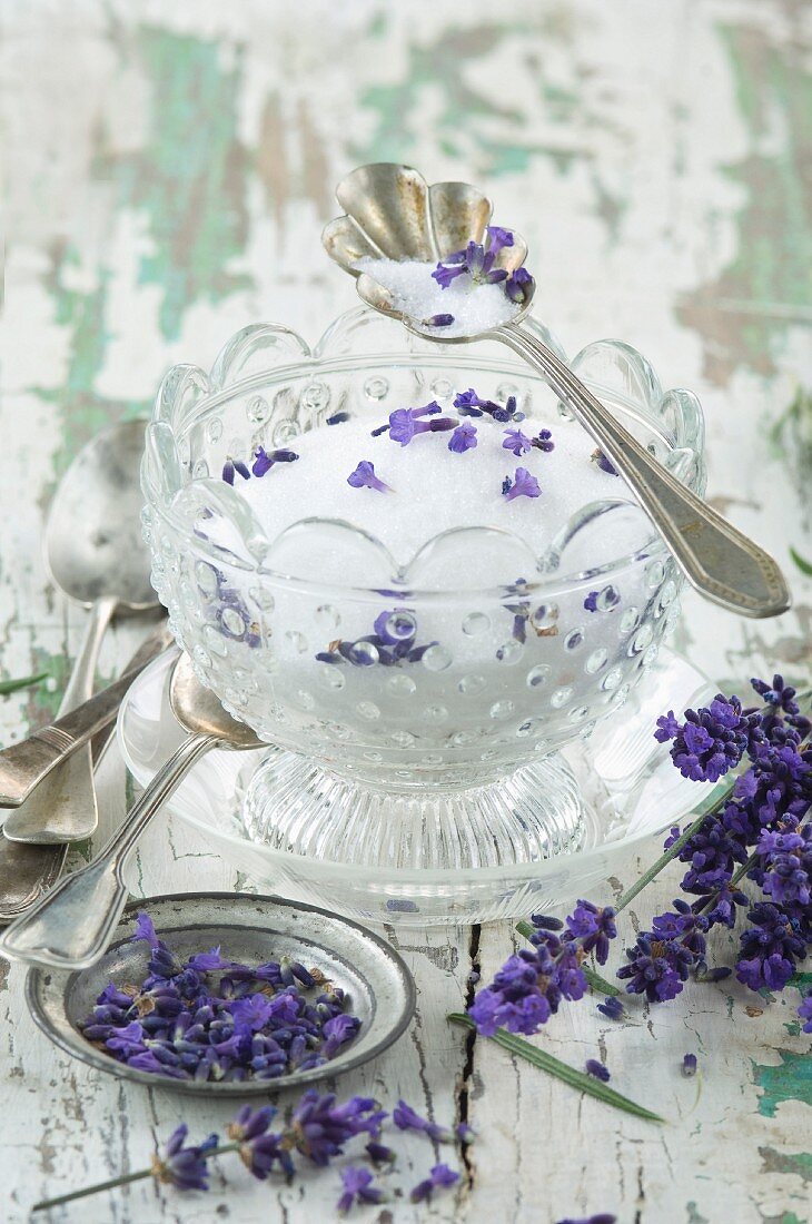 Lavendelzucker in Glasschälchen, davor frische Lavendelblüten