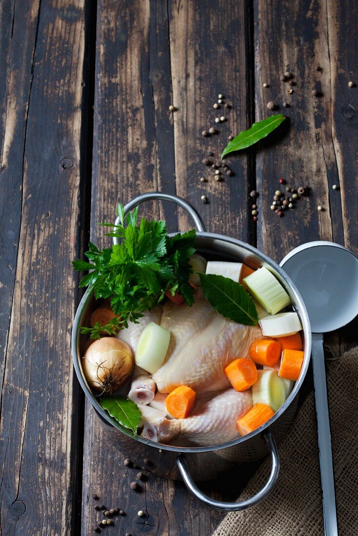 Raw corn-fed chicken with soup vegetables and herbs in a pot
