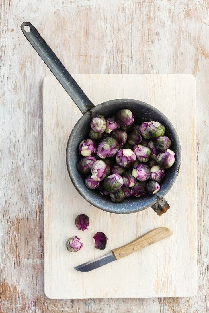 Fresh red Brussels sprouts in a pot on a chopping board (seen above)