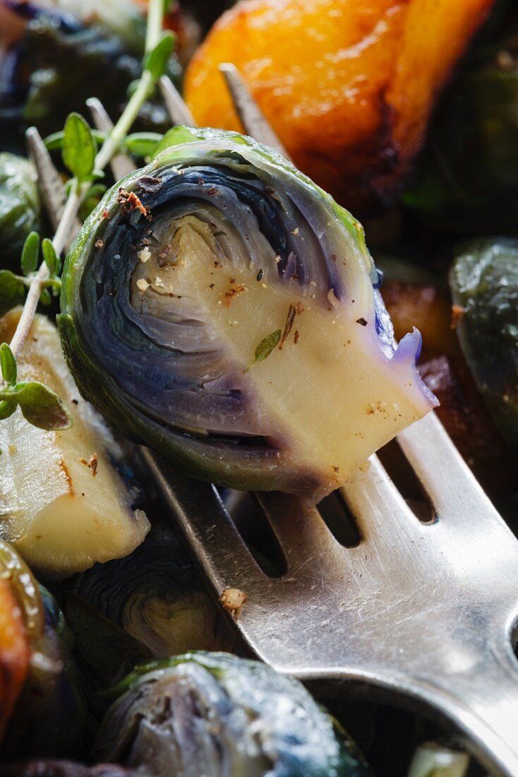 A red Brussels sprout on a fork (close-up)