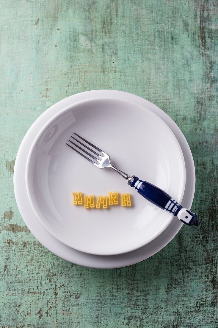 Pasta letters and a fork on a pasta plate (seen from above)