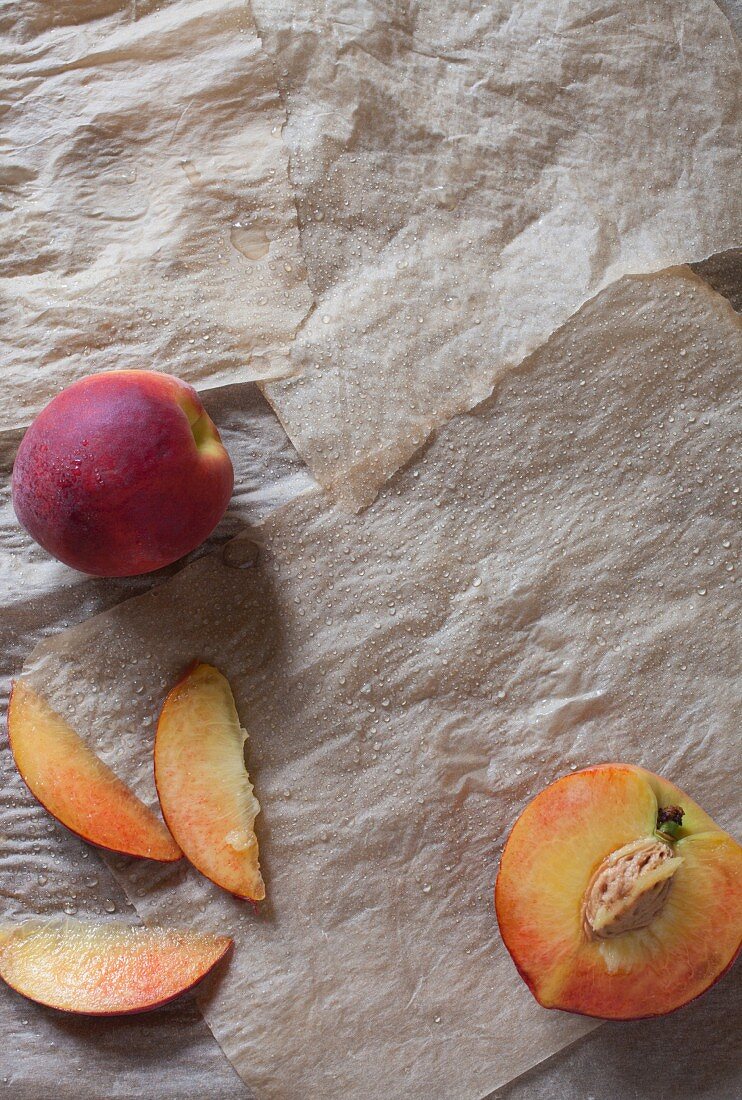 Frische Pfirsiche, ganz, halbiert und in Scheiben geschnitten (Draufsicht)