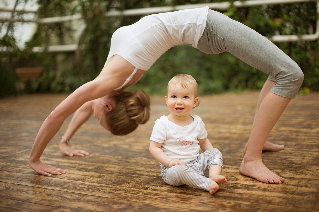 A woman practising yoga while her baby watches
