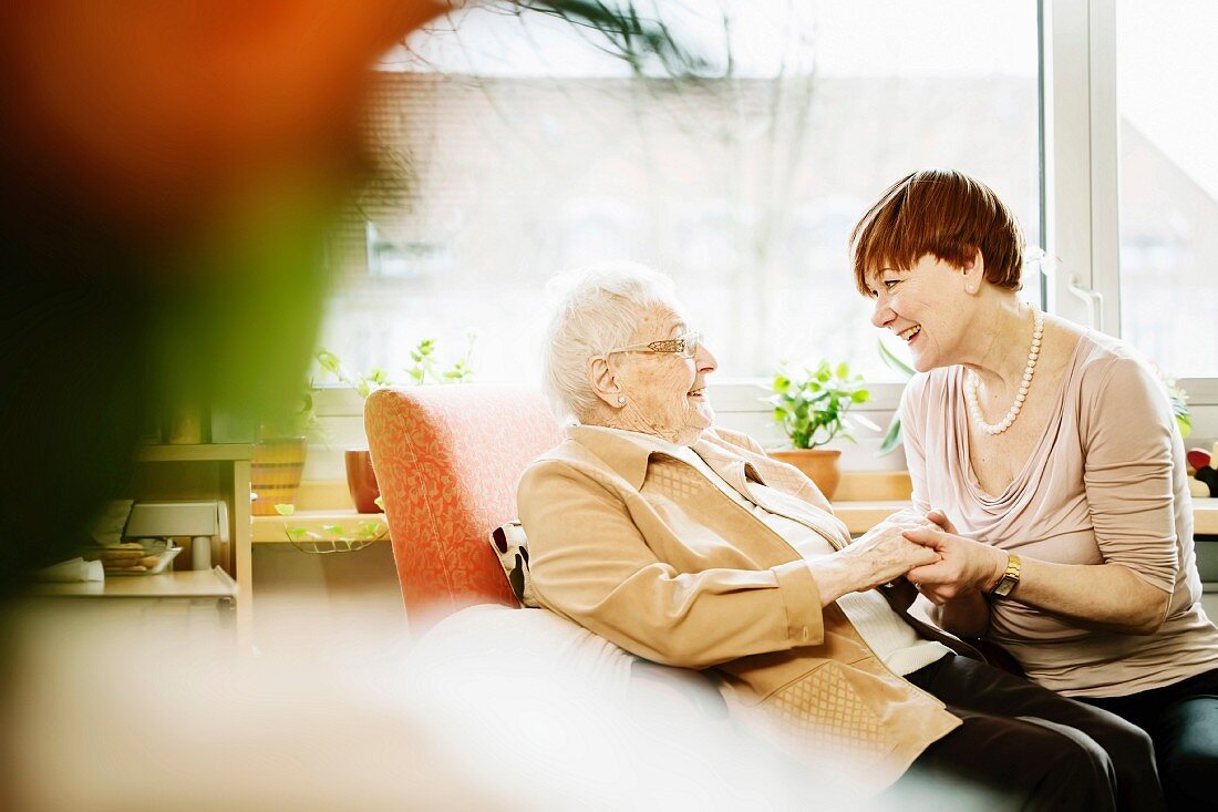 An adult daughter talking to her mother with Alzheimer's disease in a care home