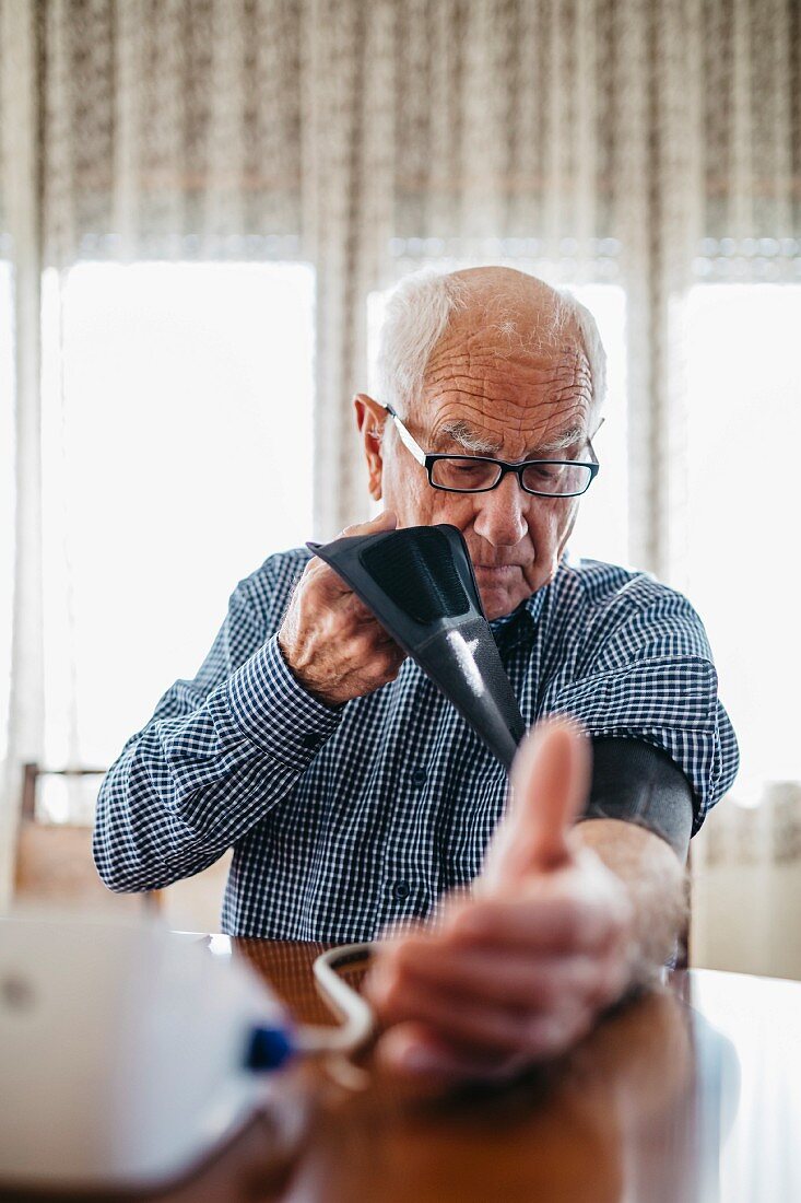 An older man measuring his blood pressure at home