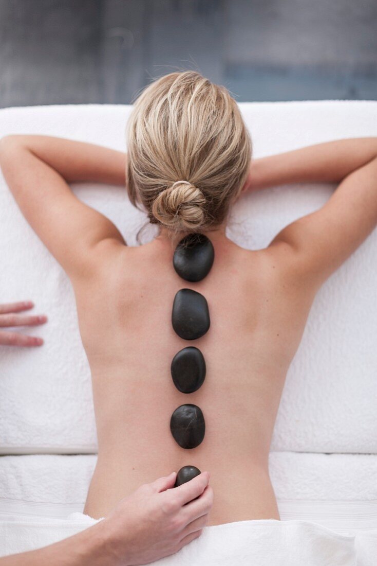 A woman receiving a hot stone massage in a spa