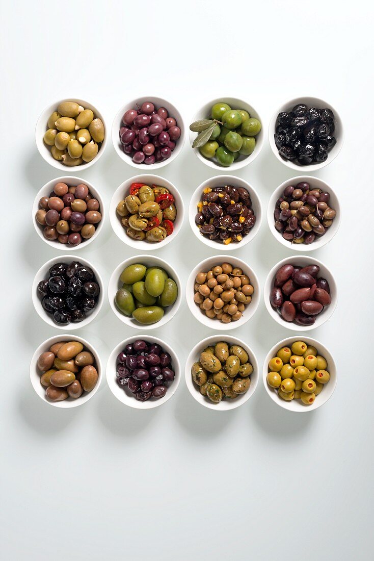 Various prepared olives in white bowls