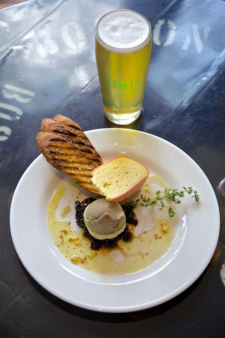 Helles Bier und Teller mit Käse, Pastete, Brombeeren, Knoblauch Oliven und geröstetem Baguette