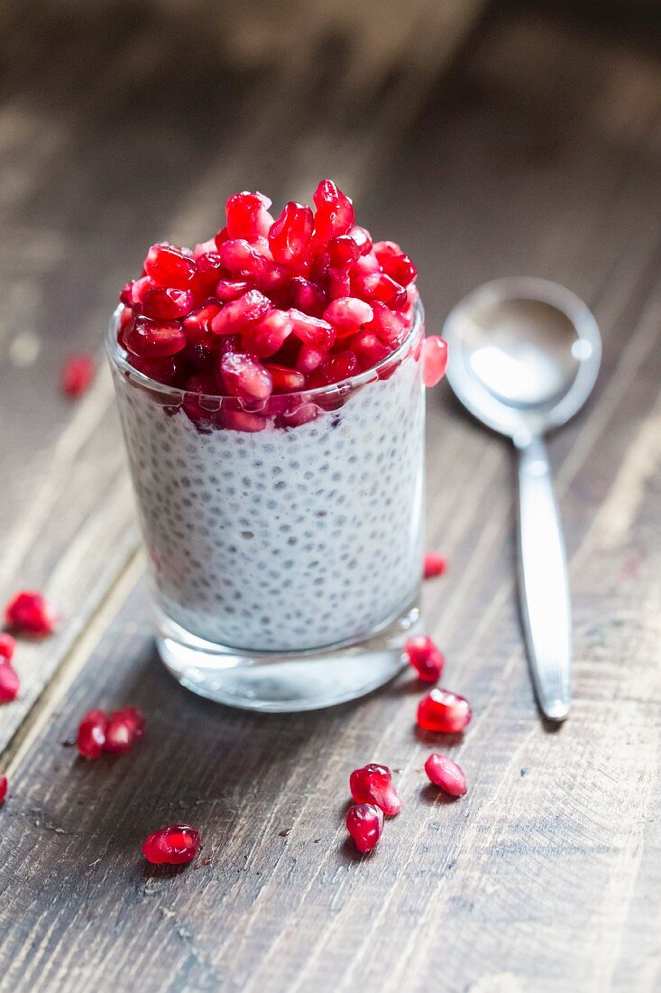 A glass of chia pudding with pomegranate seeds
