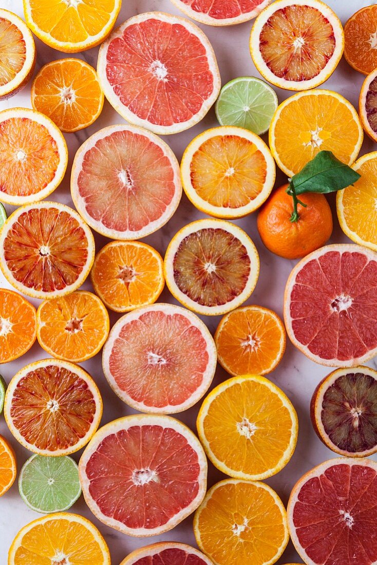 A whole mandarin surrounded by halved citrus fruits (seen from above)