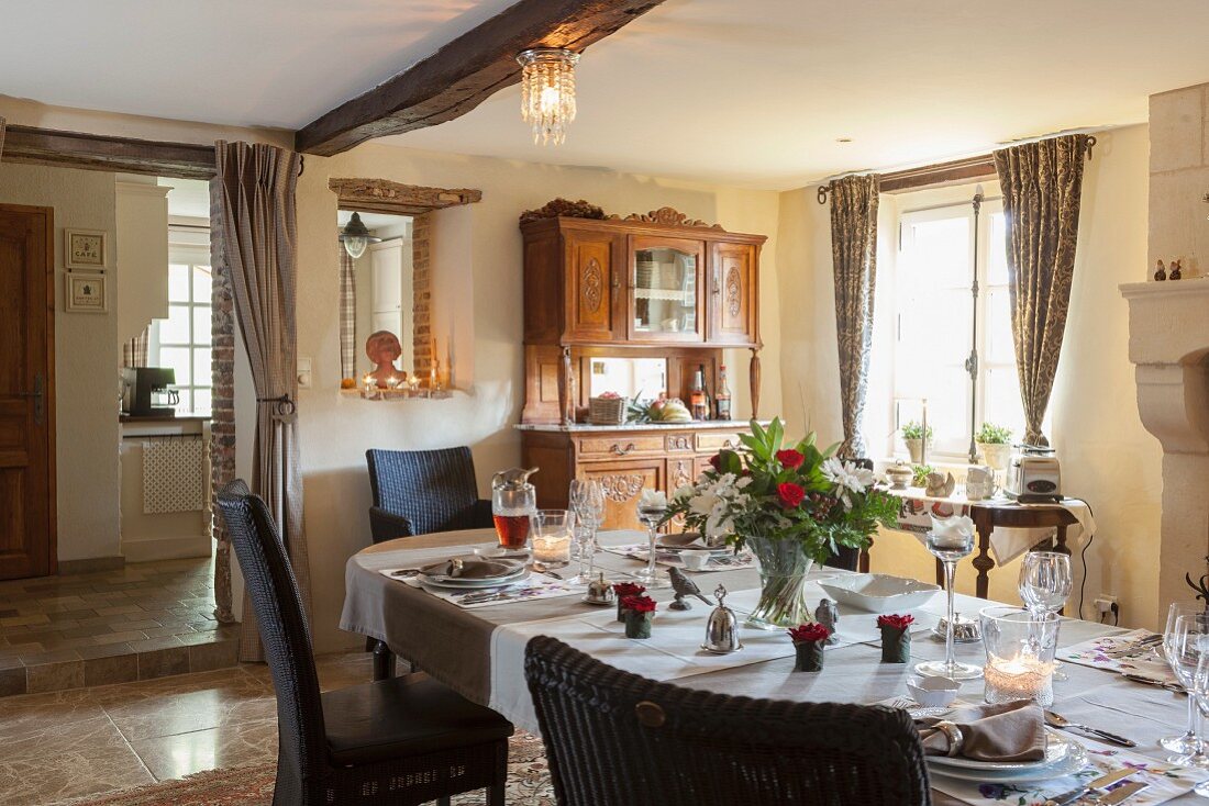 Festlich gedeckter Esstisch mit Blumendeko in ländlichem Esszimmer mit Durchgang zur Küche