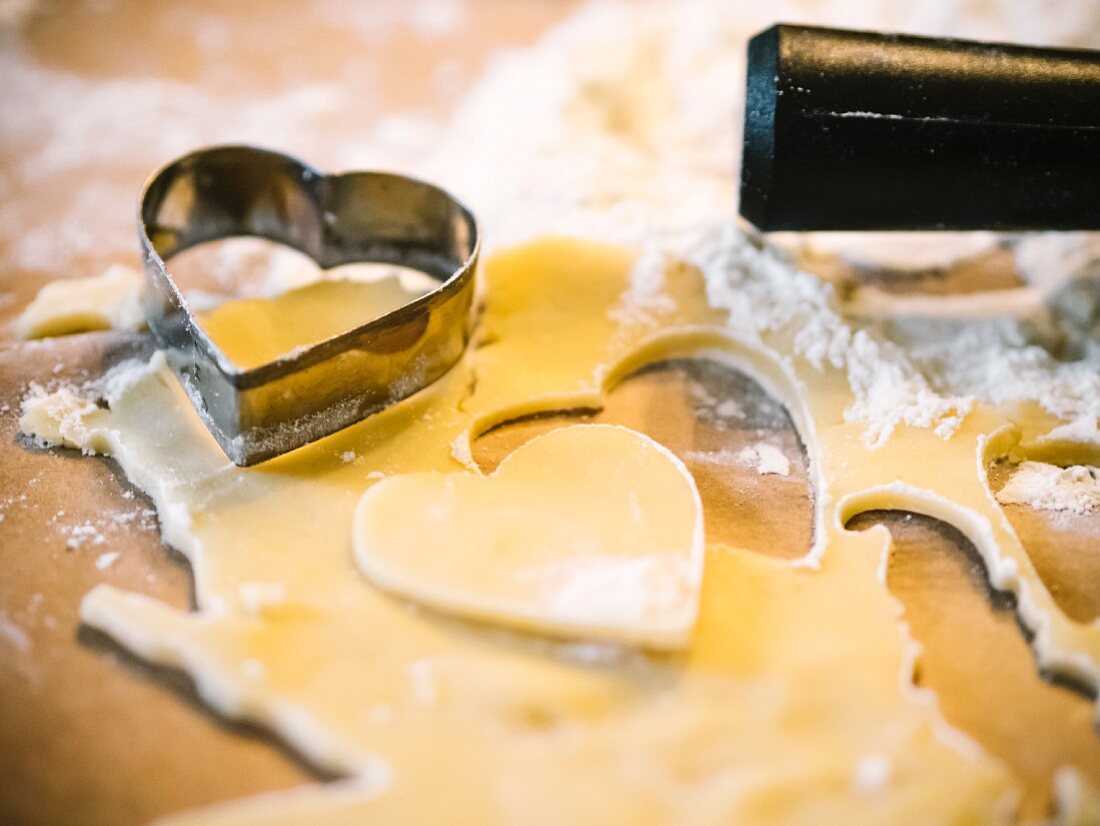 Heart-shaped biscuits being cut out of shortcrust pastry (close-up)