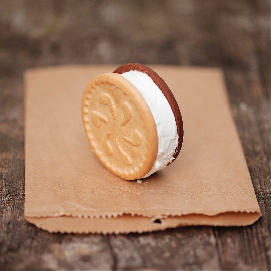 An ice cream sandwich standing upright on a paper bag