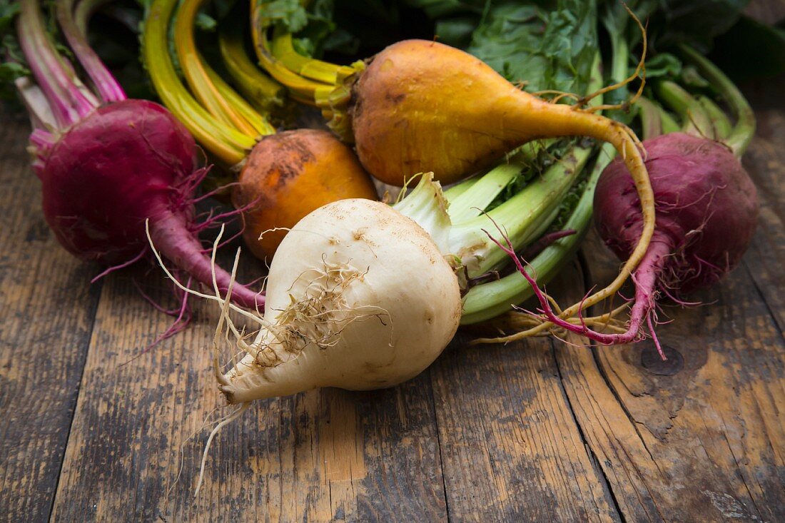 Organic beetroots, golden beets and white beets on a wooden surface