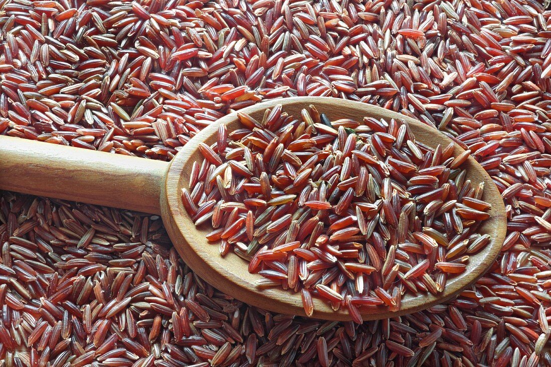 Red rice on a spoon on top of a pile of red rice