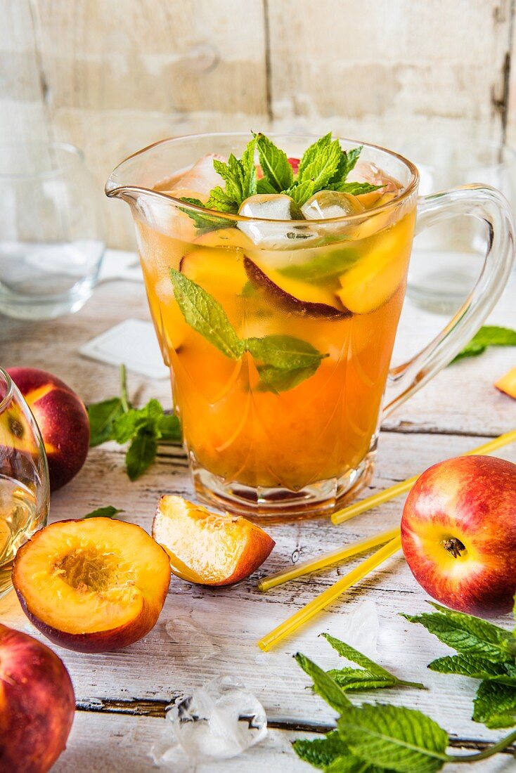 Iced tea with nectarines and mint in a glass jug