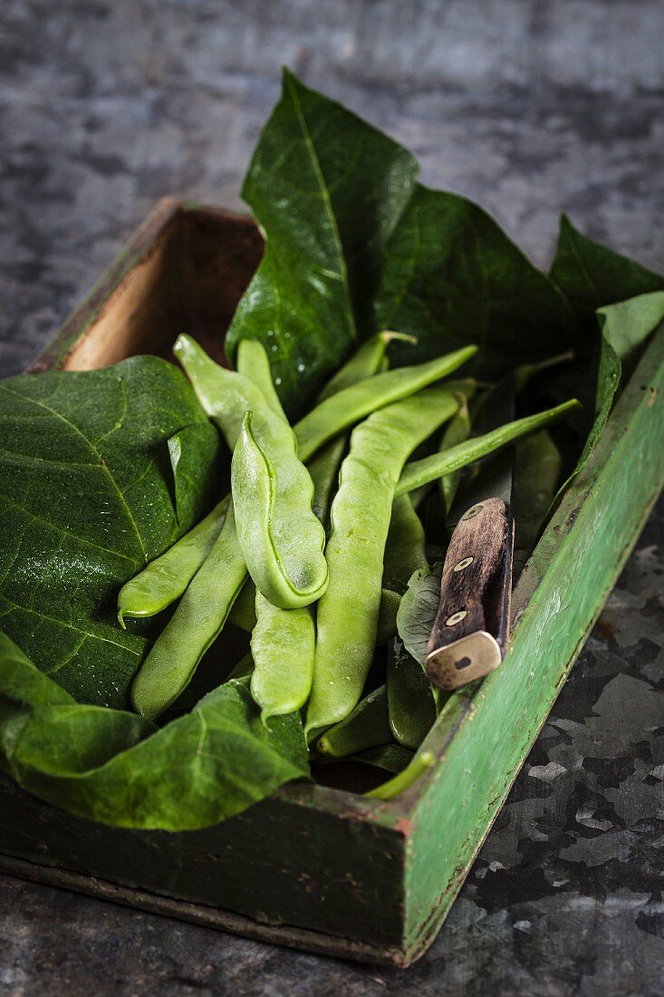 Green beans on leaves in a wooden crate