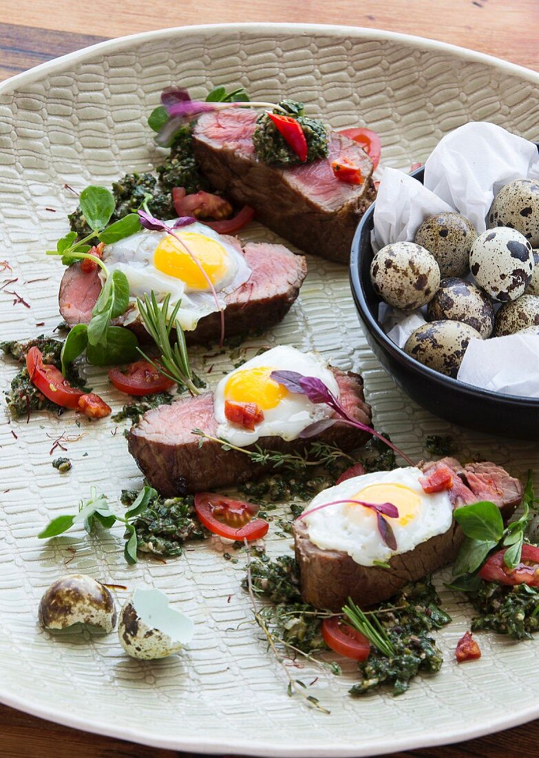 Grilled steak with fried quails eggs and salsa verde