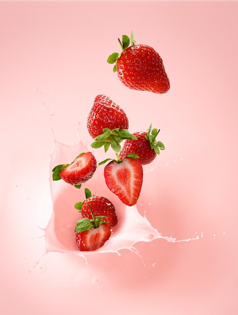 Strawberries falling into strawberry milk